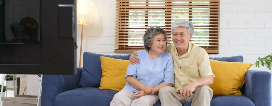 Life Assure Senior Couple Sitting On Couch Watching TV Blog